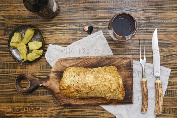 Delicious homemade roasted pork meat and pickled peppers on a rustic wooden table surrounded with