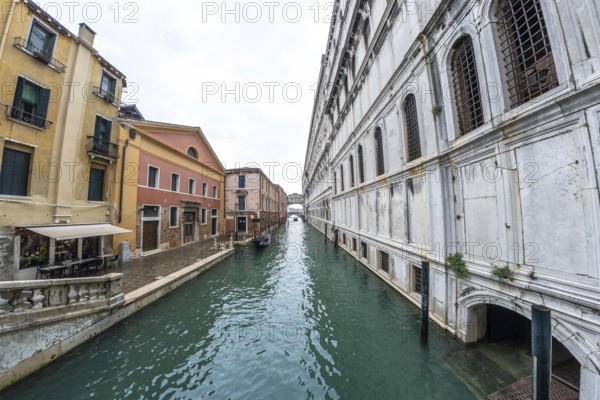 Serene canal in venice with traditional gondola navigating towards distant bridge, showcasing