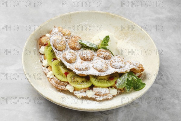 A delightful dessert showcases a fluffy shell filled with fresh kiwi slices and whipped cream,