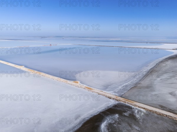 A vast salt lake under a clear blue sky, with simple geometric lines and footbridge, aerial view,