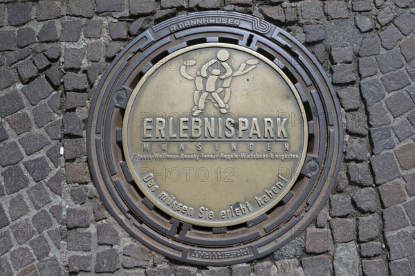 Municipal manhole cover with an advert for an adventure park, Biberach an der Riß,