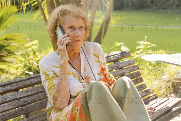 Senior woman enjoying a conversation on her mobile phone while sitting on a wooden bench in a