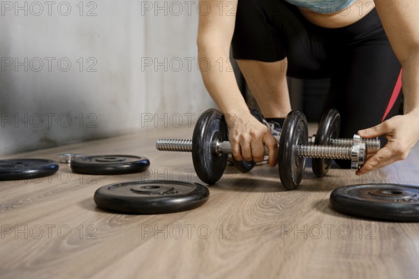 A person is adjusting weights on a dumbbell while preparing for an intense workout. The setting is