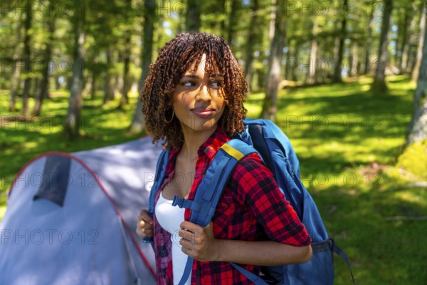 Young woman with a backpack enjoying the tranquility of a forest, discovering nature while camping