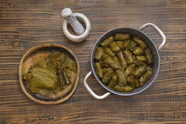 Delicious dolma is being prepared at home, featuring grape leaves wrapped around a savory filling.