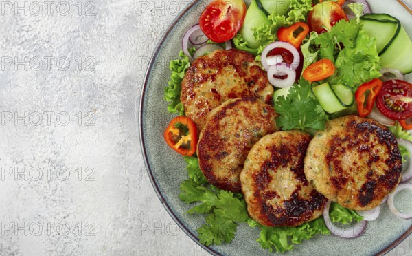 Fried chicken cutlets, minced chicken, with vegetables, on gray, with vegetable salad, top view,