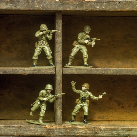 A set of classic plastic toy soldiers arranged on a wooden shelf, displaying soldiers in various