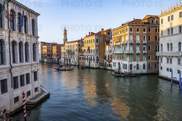 View of the Grand Canal with gondoliers at sunset, picturesque evening mood with palazzos on the