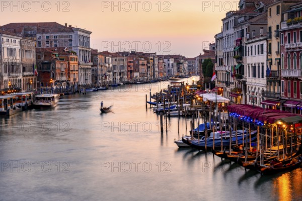 View of the Grand Canal with gondoliers at sunset, picturesque evening mood with illuminated