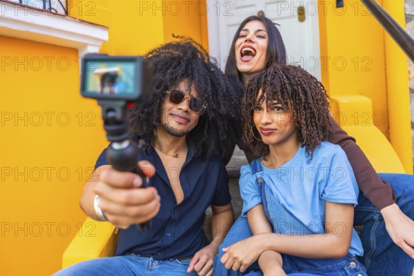 Three latin friends filming a vlog using a gimbal and action camera, enjoying laughter and smiles