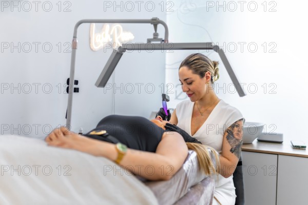 Beautician performing a permanent makeup treatment on a client's face, using a specialized device