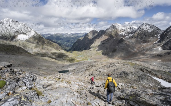 Two mountaineers in a rocky mountain landscape, descending from the summit of Keeskopf, behind them