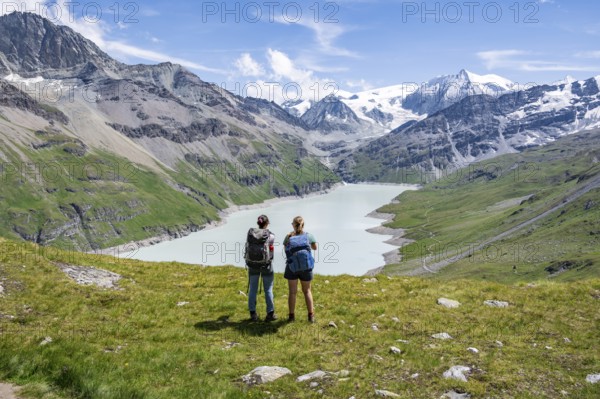 Two female friends in the mountains, mountaineers in front of a blue mountain lake, reservoir Lac