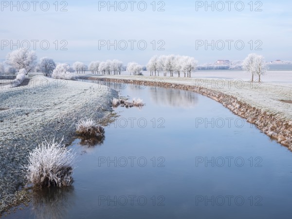 The river Unstrut in the Unstrut valley in winter, fields and trees covered with hoarfrost, behind