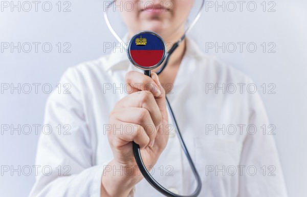 Female doctor holding stethoscope with Liechtenstein flag. National health system of Liechtenstein