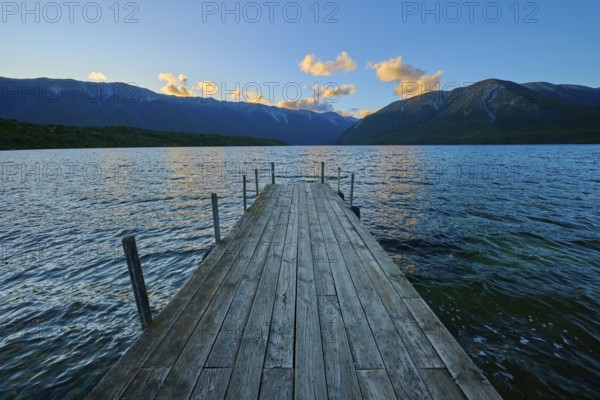 Wooden footbridge leading into a lake with mountains in the background at sunrise, summer, Lake