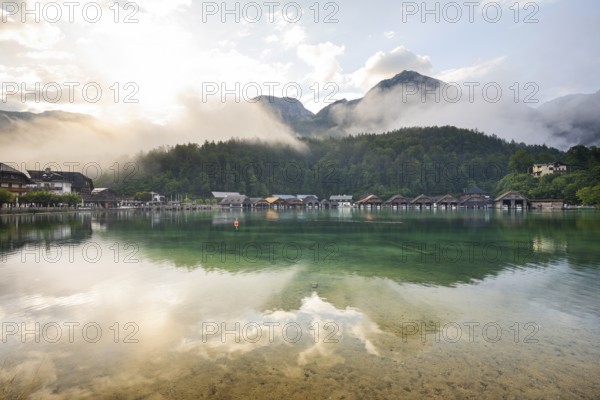 Mystical morning at Königssee in Schönau with boathouses. Sunrise and beautiful wafts of mist over