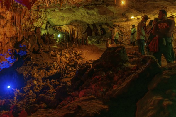 Tourists walking past limestone rock formations in a cave at Florida Caverns State Park in the
