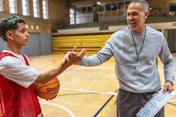 Basketball coach explaining game strategy using clipboard to young player holding ball in a