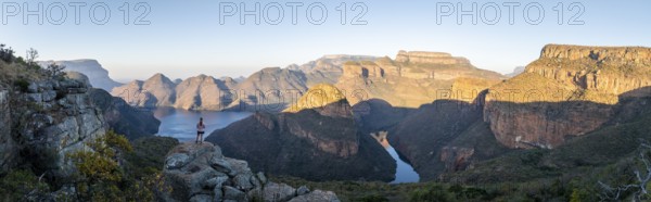 Hiker enjoying panorama, sunset at Blyde River Canyon with Three Rondawels peak, view of canyon
