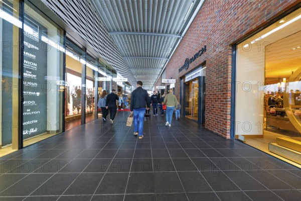 Visitors in the shopping centre surrounded by shops and modern architecture, Outlet City Metzingen,