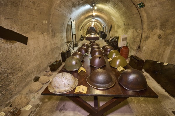 Table with various helmets in a long tunnel exhibition area, steel helmets, war museum, military