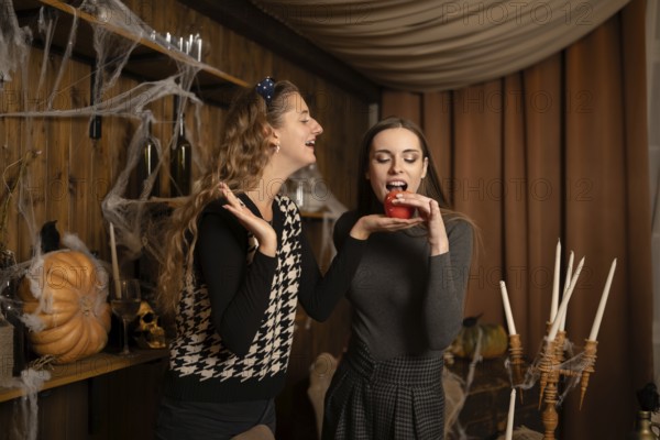 Two friends are playfully engaging in a Halloween celebration, surrounded by festive decorations.