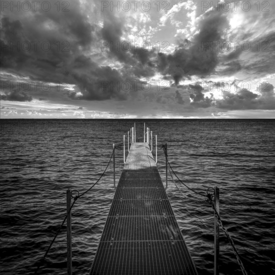 A serene jetty stretches over the calm waters of Lake Geneva, surrounded by dramatic skies filled
