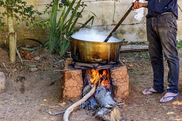 Person preparing a meal in the backyard on a wood-burning stove typically used in Minas Gerais,