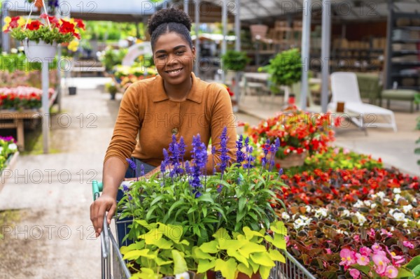 Smiling afro american woman pushing a shopping cart filled with vibrant flowers while browsing in a
