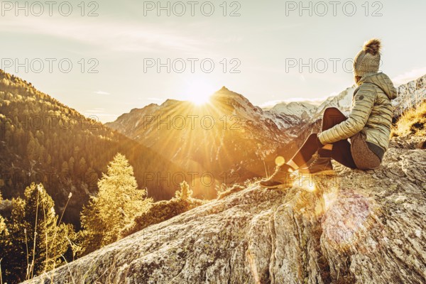 Woman sitting thoughtfully at a feslen at autumn atmosphere during sunset in the Swiss Alps in the