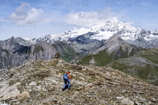 Mountaineer on a hiking trail, snow-covered and glaciated summit of the Großglockner in the