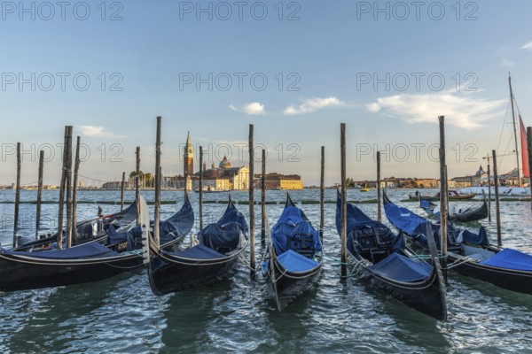 Gondolas moored at sunset with the island of san giorgio maggiore in the background, creating a