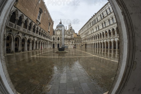 Wet pavement reflecting surrounding historical architecture in doge's palace courtyard on a rainy