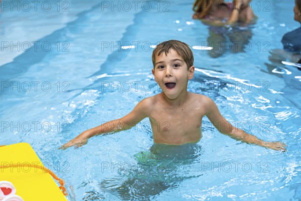 Young boy enjoying his summer vacation, playing and making funny faces in a swimming pool with a
