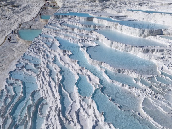 Detailed photo of cascading limestone terraces with turquoise-coloured water, aerial view, sinter