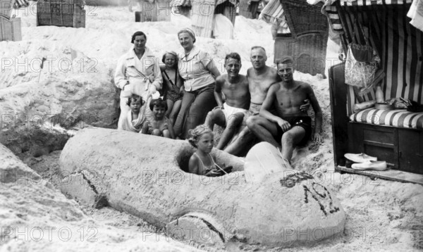Sand car beach chair family, 1930s, family on the beach posing around a large sand car, relaxed and
