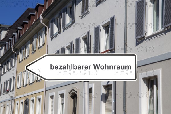 (Photomontage) Sign with the inscription BEZAHLBARER WOHNRAUM in front of municipal apartment