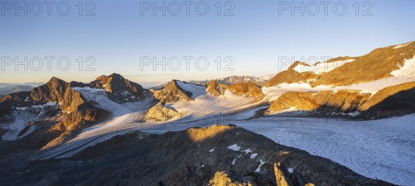 Picturesque high mountain landscape at sunrise with alpenglow, glacier and rocky mountain peaks in