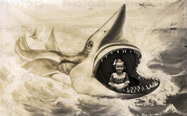 Girl posing for a photo in the painted mouth of a shark. Kitsch. ca. 1920s, location unknown