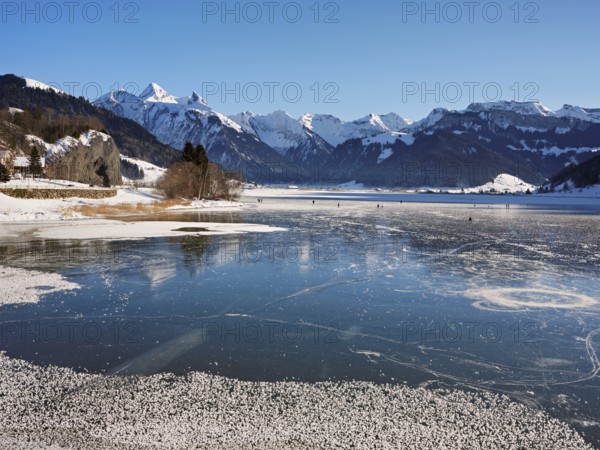 Frozen Sihlsee, reservoir, behind the snow-covered mountains Flübrig and Druesberg, Euthal, Canton
