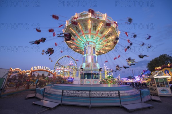 Lively carousel illuminated at a night fair, chain carousel, spring festival, Cannstatter