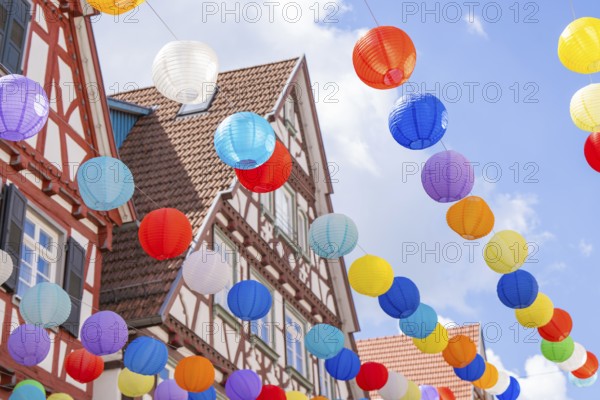 Lively balloons float above traditional half-timbered houses in a clear blue sky, Calw, Black