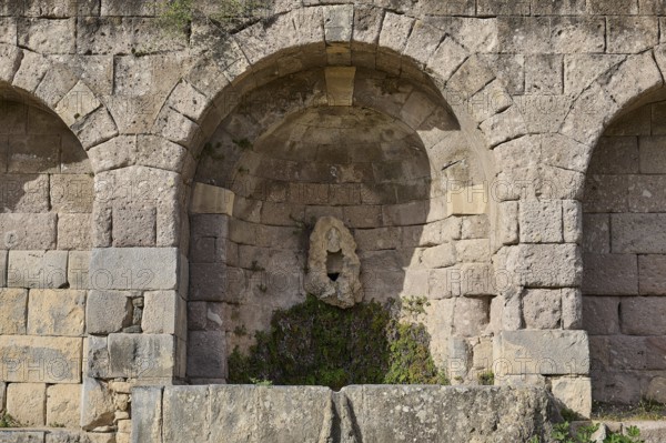 Ancient round arches with a sculpture and moss growth, arcade, lower terrace, Pan, Asklipion,