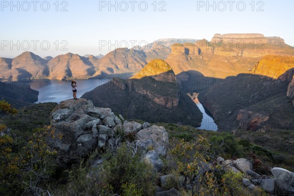 Hiker enjoying sunset at Blyde River Canyon with Three Rondawels peak, view of canyon with Blyde