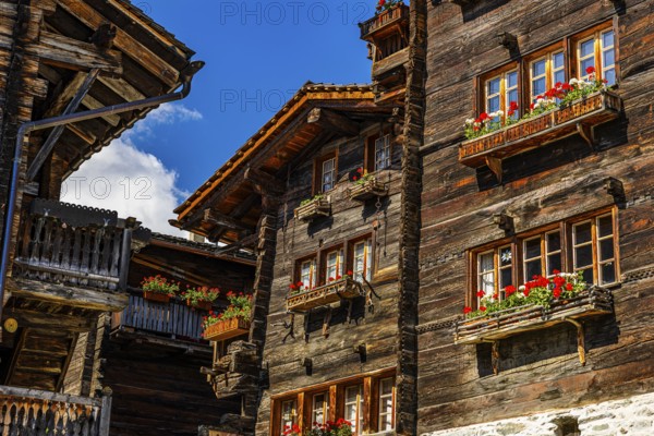 Old wooden houses in log construction, decorated with flowers, historic village centre, Grimentz,