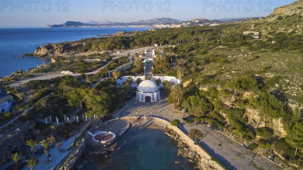 Drone shot, morning light, aerial view with domed building in green coastal landscape on the blue