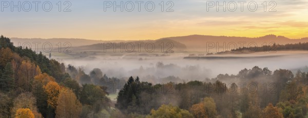 Landscape in Franconian Switzerland in autumn, view over colourful forests with morning mist at