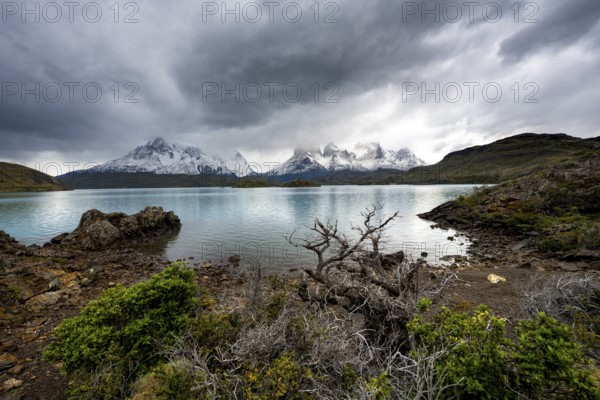 Cloudy mountain range Cuernos del Paine, shore of the blue lake Lago Pehoe in the evening light,