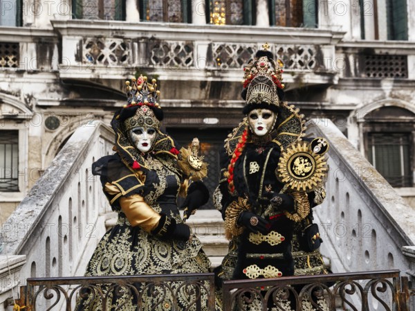 Two people in costume posing on a staircase, Venetian costumes with masks, Carnival in Venice,